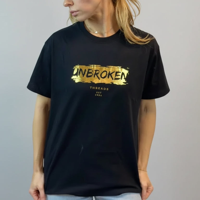 Person wearing a black t-shirt with gold text on a plain background