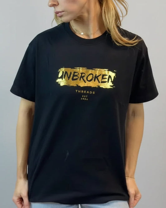 Person wearing a black t-shirt with gold text on a plain background